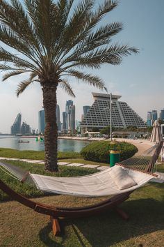 a hammock and palm trees in front of a cityscape on the beach