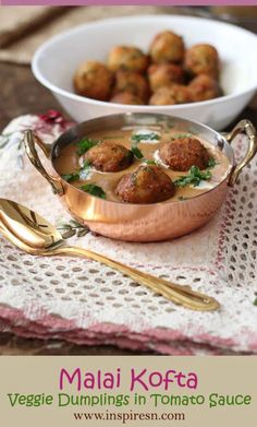 some food is in a metal bowl on a table with gold spoons and utensils