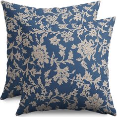 two blue and beige pillows with white floral designs on the front, one in gold