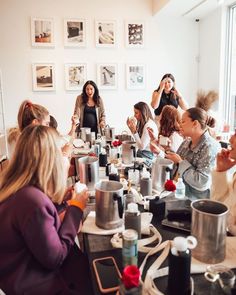 a group of women sitting around a kitchen table with pots and pans on it