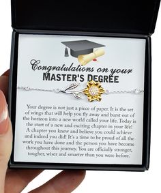 a hand holding a graduation necklace with congratulations on your master's degree