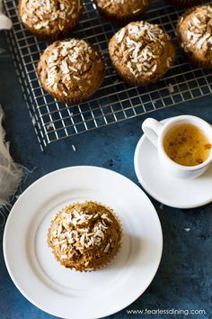 muffins with coconut flakes on a plate next to a cup of tea