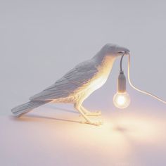 a white bird lamp with a light bulb on it's head and its body turned upside down