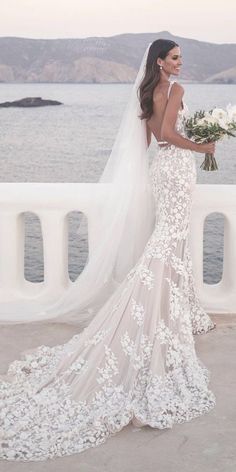 a woman in a wedding dress standing by the water