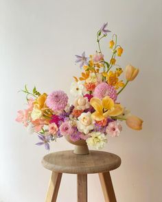 an arrangement of flowers in a vase on a stool