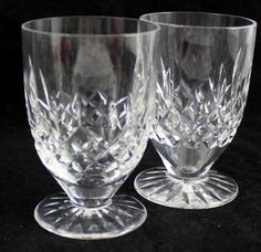 two clear glass goblets sitting next to each other on a black tablecloth