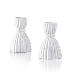 two white vases sitting next to each other on a white surface with reflections in the floor