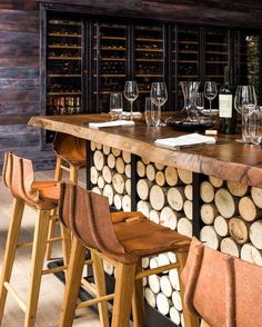 wine glasses are lined up on the bar with wooden stools in front of them