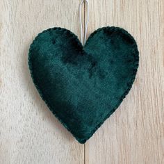 a dark green heart hanging on a wooden wall with a metal hook attached to it