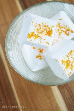 four pieces of marshmallow sitting on top of a glass plate with orange sprinkles