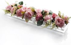 pink roses and greenery are arranged on a clear glass vase with water in it