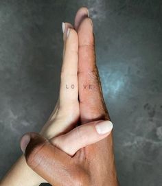 two people holding hands with the word love tattooed on their fingers