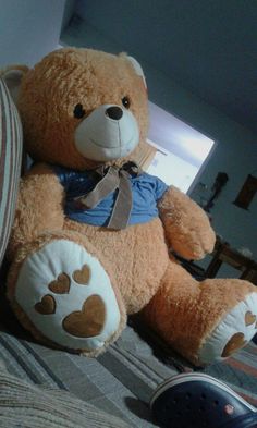 a brown teddy bear sitting on top of a bed