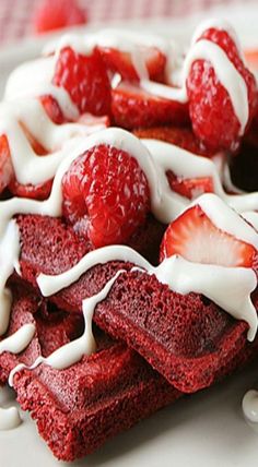 a white plate topped with red velvet waffles covered in whipped cream and strawberries