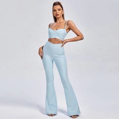 a woman in a blue two piece top and wide legged pants with her hands on her hips