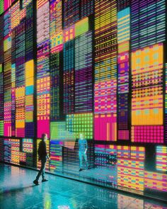 people are walking in front of an art installation with colorful squares on the wall behind them