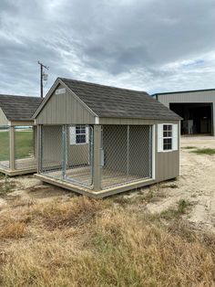 two chicken coops in the middle of an open field with grass and dirt around them