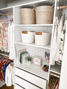 an organized closet with baskets, clothes and other items on shelving unit shelves in white