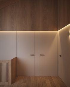 an empty room with wooden flooring and white cupboards on either side of the wall