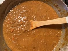 a wooden spoon in a pot filled with brown sauce on top of an electric stove