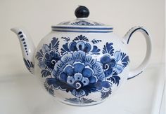 a blue and white tea pot with flowers on it