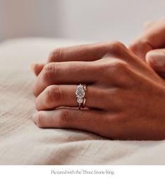 a woman's hand with a diamond ring on her left hand and the other hand holding an engagement ring