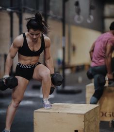 a woman squatting on top of a wooden box while holding two dumbbells