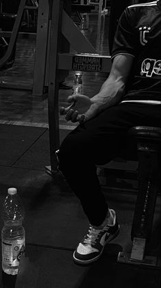 a man sitting on a bench next to a bottle of water