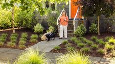 a woman walking two dogs on a leash down the steps in front of her house