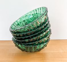 a stack of green glass bowls sitting on top of a wooden table