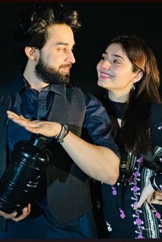 a man and woman standing next to each other with a birthday card in front of them