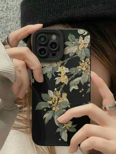 a woman holding up her phone case with flowers on it