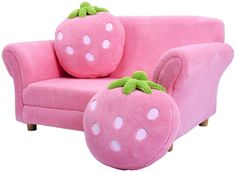 a pink couch with two stuffed strawberries on it's back and one sitting in the middle