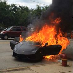 a car that is on fire with it's hood up in the middle of the street