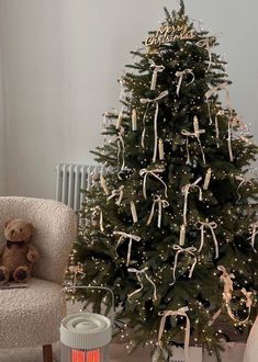 a decorated christmas tree in a living room with a teddy bear sitting next to it