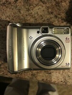 a silver camera sitting on top of a counter next to a cat's paw