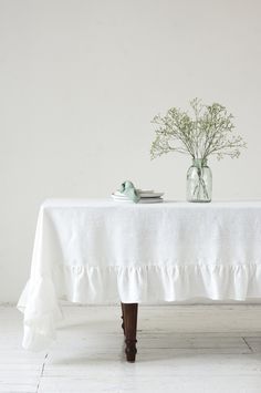 a table topped with a vase filled with flowers and two plates on top of it