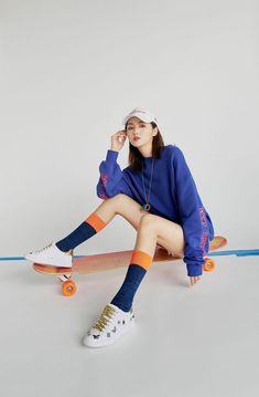 a young woman sitting on top of a skateboard