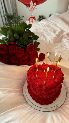 a red heart shaped cake sitting on top of a bed