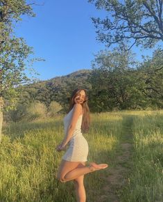 a woman is standing in the grass with her legs spread out and one leg up