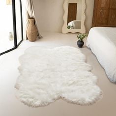 a large white rug is in the middle of a room with a bed and mirror