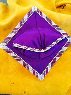 a purple and white diamond shaped object sitting on top of a yellow blanket