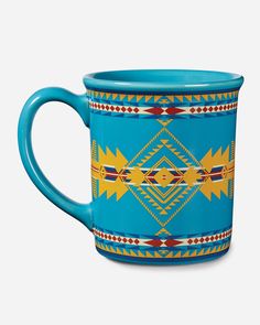 a blue and yellow coffee mug with an intricate design on the outside, in front of a white background