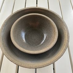 two bowls sitting on top of each other on a white wooden table next to another bowl