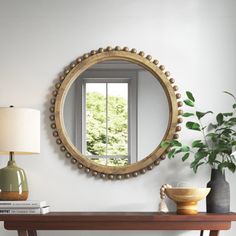 a mirror on the wall above a table with a vase and lamp next to it