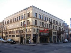 an old building on the corner of a street with cars parked in front of it