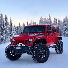 a red jeep is driving through the snow