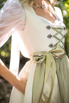 A bridal dirndl is a truly unique, elegant and fashionable way to celebrate your wedding day. Whether you are wearing it for your ceremony, reception or your rehearsal dinner, a made-to-order bridal dirndl is a perfect choice! Available in white or ivory, this bridal dirndl is sure to turn heads at your Oktoberfest-themed wedding Ivory or white satin bridal dirndl Pleated skirt length is 26" from the waist to the hemline 2 skirt pockets Classic square neckline with matching ivory piping Ribbon and chain lace-up bodice Elegant poly chiffon apron with wide ribbon apron ties Pictured with the Sweetheart Blouse with Draped Sleeves in white and Dirndl Petticoat - Last photo pictured with Tulle Top Skirt This dirndl made to order. Please allow 8-10 weeks for delivery Made with love in Chicago, I Oktoberfest Wedding, Bridal Dirndl, Wedding Dirndl, Square Necklines, Rehearsal Dinners, British Indian, Square Neckline, White Wedding, Vogue