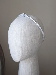 a white mannequin headpiece with silver beading on it's sides