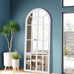 a living room with blue walls and a white arched window on the wall next to a potted plant